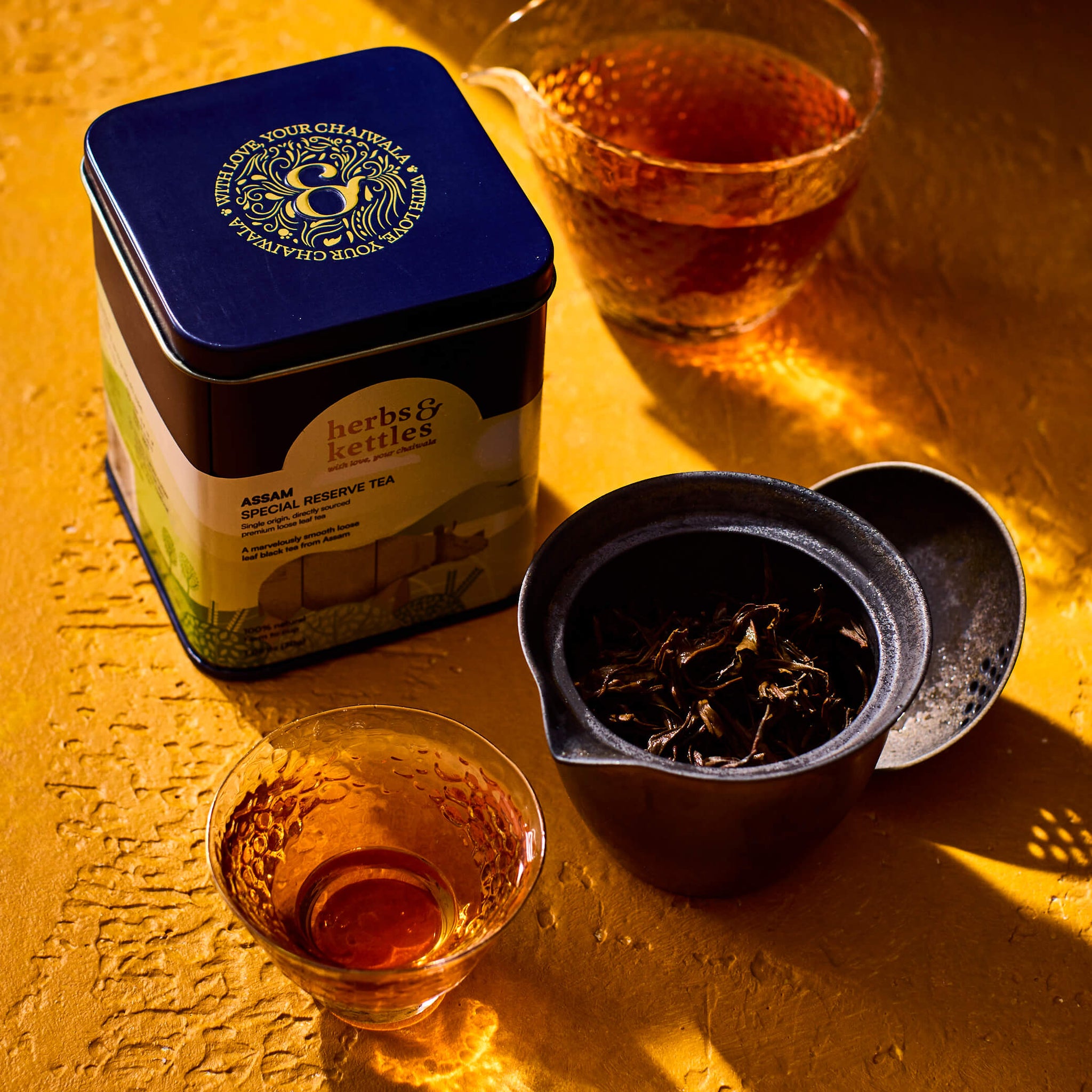 a tin of Assam Special Reserve with loose leaf next to the glass of Assam Special Reserve tea